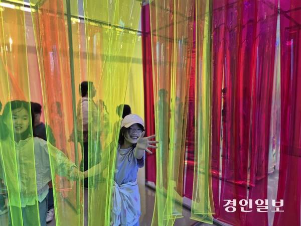김포아트빌리지 내 한옥마을을 찾은 한 학생이 다채로운 빛과 색으로 꾸며진 기획전시 ‘비밀의 정원’을 관람하며, 손을 흔들고 있다. /김포문화재단 제공