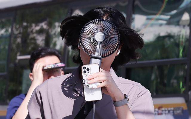 폭염이 연일 이어지는 10일 서울 종로구 광화문 광장 인근에서 한 시민이 손선풍기를 얼굴에 대며 출근하고 있다. 뉴스1