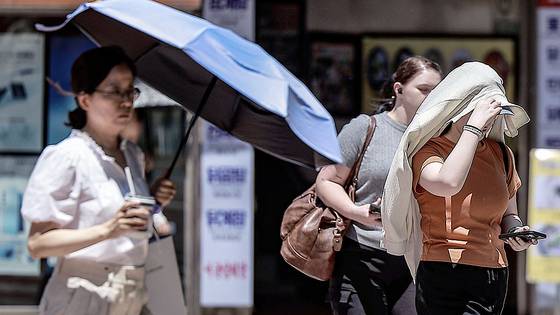 폭염이 이어진 10일 서울 중구 을지로3가역 인근에서 한 시민이 겉옷으로 햇빛을 가린 채 이동하고 있다. 뉴시스