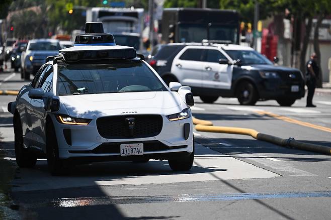 A Waymo autonomous self-driving Jaguar electric vehicle sits parked on the side of the road after the path of travel was blocked by fire hoses and emergency vehicles as Los Angeles Fire Department (LAFD) firefighters responded to a fire in a dumpster in Los Angeles, California on May 8. [AFP/YONHAP]