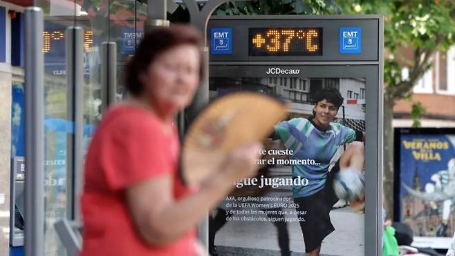 1일(현지시간) 스페인 마드리드의 폭염 속 37도의 온도를 보여주는 버스 정류장에서 한 여성이 부채질로 더위를 식히고 있다. /AFPBBNews=뉴스1