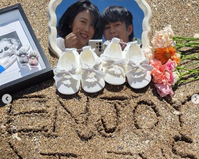 임라라와 손민수가 해변에 아기 신발과 임신 테스트기를 올려두고 사진을 찍고 있다. / 임라라 SNS