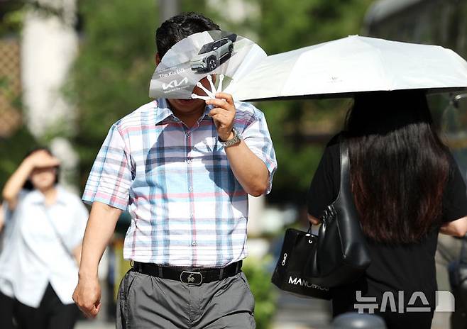 [서울=뉴시스] 조성우 기자 = 폭염이 계속되는 10일 서울 종로구 거리에서 한 시민이 부채로 햇볕을 피하며 이동하고 있다. 2025.07.10. xconfind@newsis.com