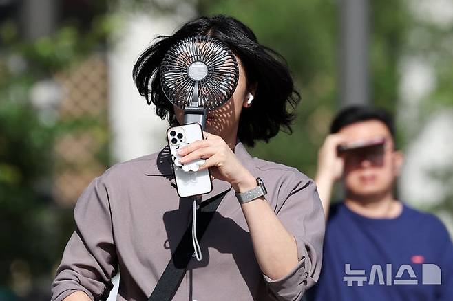 [서울=뉴시스] 조성우 기자 = 폭염이 계속되는 10일 서울 종로구 거리에서 한 시민이 선풍기로 더위를 식히며 이동하고 있다. 2025.07.10. xconfind@newsis.com