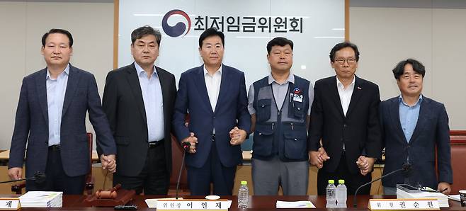 10일 저녁 세종시 정부세종청사 고용노동부에서 열린 최저임금위원회 제12차 전원회의 참석자들이 손을 잡고 기념촬영을 하고 있다. /뉴스1