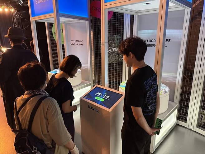 지난 10일 일본 오사카 엑스포에 마련된 ‘네이버 AI 페스티벌: 기술로 연결하는 미래' 전시에서 '디지털 트윈' 기술 체험 부스를 찾은 관람객들이 설명을 듣고 있다. 사진=주원규 기자