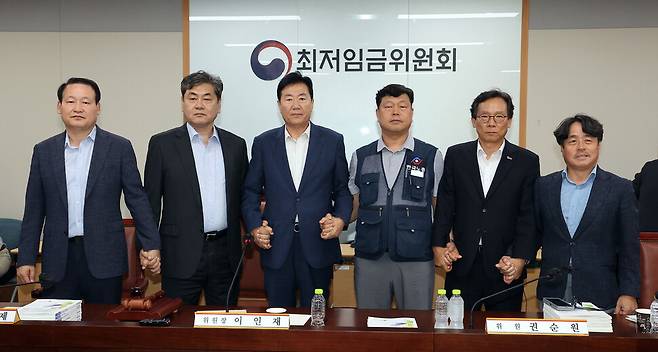 10일 정부세종청사에서 열린 제12차 전원회의에서 내년 최저임금을 시간당 1만320원으로 17년만에 합의로 결정한 공익위원-사용자위원-근로자위원들이 손을 잡고 기념촬영을 하고 있다. 연합뉴스