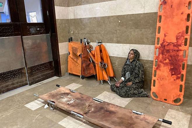 8일(현지시각) 가자지구 남부 칸유니스 인근에서 벌어진 이스라엘군의 폭격 뒤 한 여성이 나세르 병원 바닥에 앉아 있다. AFP 연합뉴스