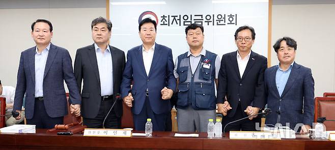 [세종=뉴시스] 강종민 기자 = 최저임금위원회 이인재 위원장과 권순원 공익위원, 류기정 사용자 위원, 류기섭 근로자 위원 등이 지난 10일 밤 세종시 정부세종청사에서 2026년도 적용 최저임금안을 합의로 결정한 뒤 손을 맞잡고 있다. 내년도 최저임금은 1만 320원으로 결정됐다. 2024.07.11. ppkjm@newsis.com