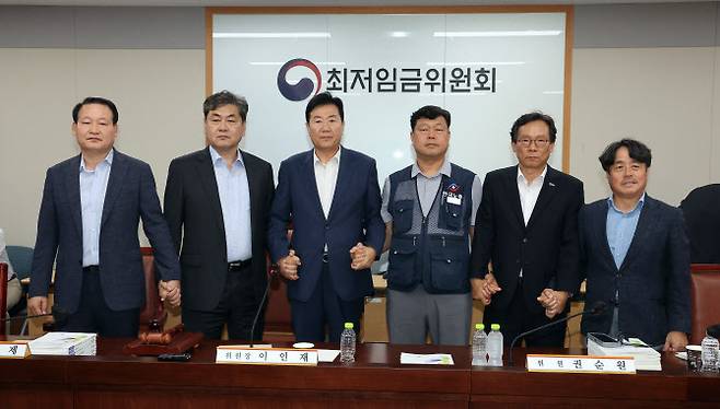 이인재 최저임금위원장(왼쪽 두 번째)이 10일 정부세종청사에서 열린 제12차 전원회의에서 내년 최저임금을 시간당 1만320원으로 17년만에 합의로 결정한 뒤 공익위원-사용자위원-근로자위원과 손을 잡고 있다.(사진=연합뉴스)