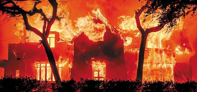 지난 1월 미국 LA 산불로 주택 한 채가 불타고 있다. 저자는 "산불 발생 당시 물적 피해보다 연기로 공기 질이 악화되면서 추가로 발생하는 시민들의 건강 악화 등 '보이지 않는 비용'에 더 주목해야 한다"고 말한다. /AFP 연합뉴스