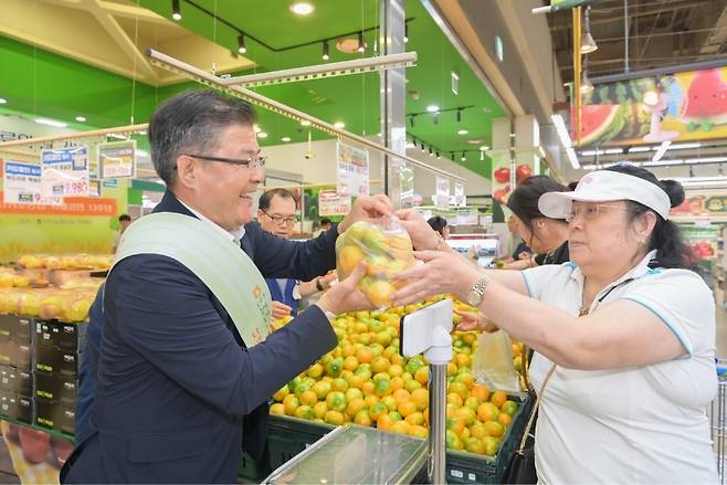 정기철 서귀포농협 조합장이 7일 서울 양재 농협유통센터에서 열린 판촉행사에서 시민에게 감귤을 전달하고 있다. 이번 행사는 농협유통과 자매결연 13주년을 기념해 마련됐다. (제주농협 제공)