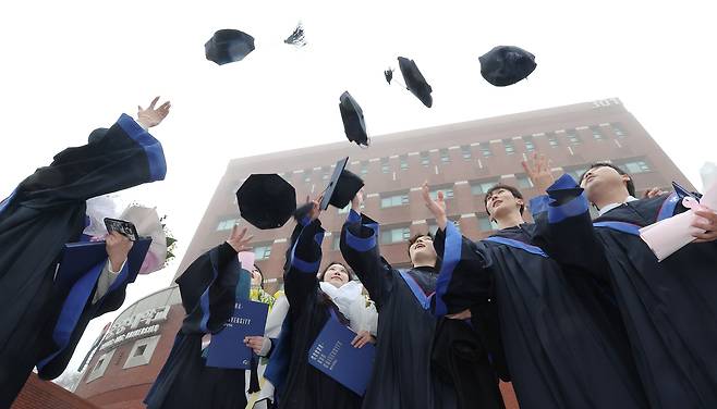 Chung-Ang University graduates throw their graduation caps in the air during their graduation ceremony held on Feb. 19, 2024. [YONHAP]