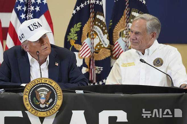 [커빌(텍사스주)=AP/뉴시스]도널드 트럼프 미국 대통령이 11일(현지 시간) 미 텍사스주 커빌의 힐 컨트리 청소년이벤트센터에서 간담회를 열고 발언하는 모습을 그레그 애벗 텍사스 주지사가 지켜보고 있다. 2025.07.12.