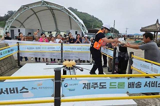 지난해 7월 제주 제주시 비양도 주민이 드론으로 배달된 치킨을 건네받고 있다. 제주도 제공