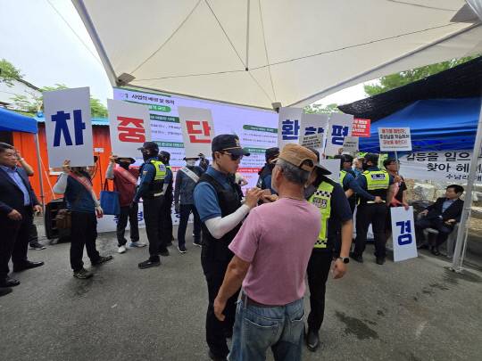 14일 오전 천안시 동면 수남1리 마을회관 앞 공터에서 열린 '사업장폐기물 매립시설 조성사업 환경영향평가서 초안 주민설명회'에서 매립장 반대 주민들과 환경단체가 손팻말로 사업설명 영상을 가리며 반대구호를 외치고 있다. 박하늘 기자