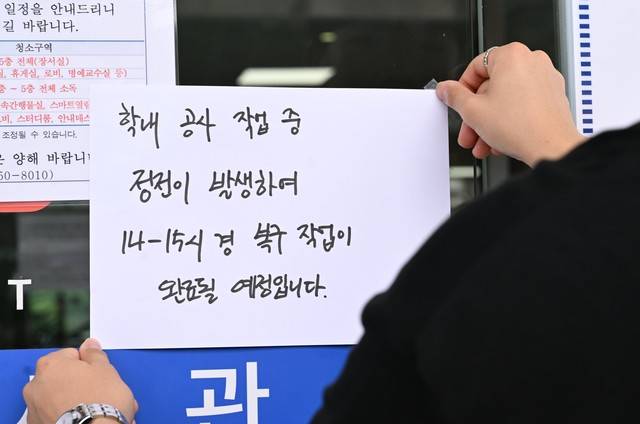 ▲14일 강원대학교 중앙도서관 앞에 대학관계자가 정전 안내문을 붙이고 있다. 이날 농생대 부근 공사현장에서 발생한 고압케이블 소손사고로,대학본부 등 대학건물 44개동에 정전이 발생한 것으로 추정된다. 김정호 기자