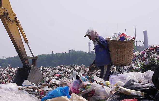 지난 4월24일(현지시간) 인도네시아 그레식 지역의 응기픽(Ngipik) 쓰레기 선별장 옆에서 유윤(48)이 쓰레기를 헤치고 있다. 유혜민 감독 제공