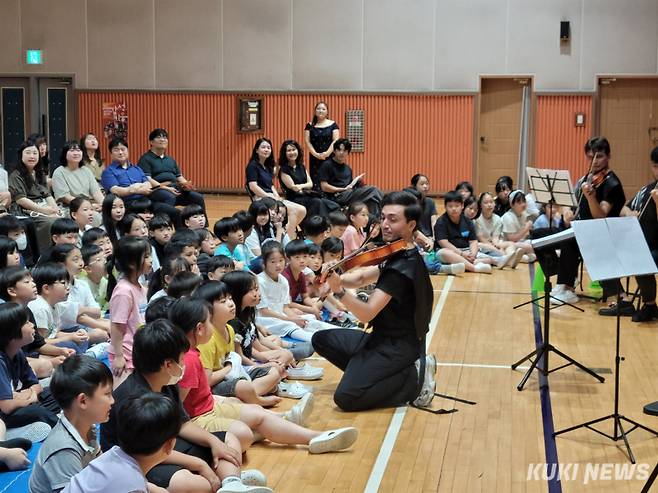 우즈베키스탄 국립 체임버 오케스트라가 '감성키움 찾아가는 음악회'로 초등학교를 방문해 학생들과 같이 어울려며 연주를 들려주고 있다.