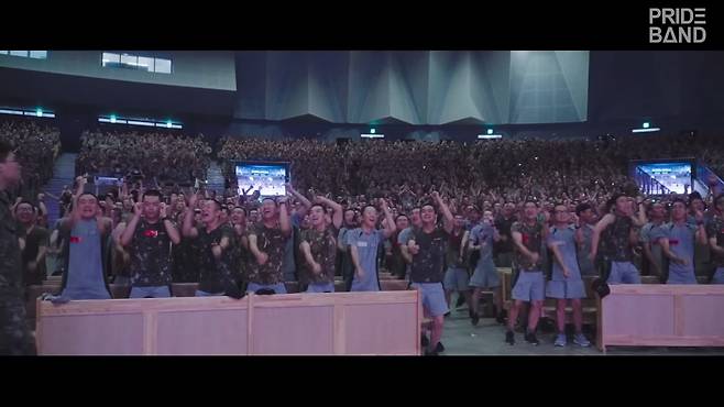 '프라이드밴드'의 공연을 관람하는 군 장병들이 뜨겁게 환호하고 있다. 장병들은 두 팔을 번쩍 들거나 함성을 지르는 등 열광적인 반응을 보이고 있다. DSM엔터테인먼트 제공