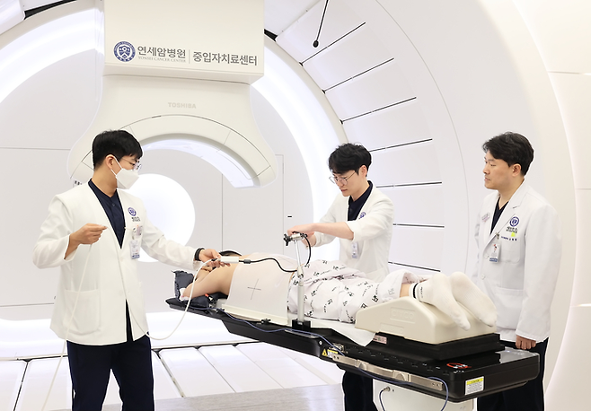 세브란스 의료진이 중입자 치료기에 엎드려있는 환자를 살피고 있다. [제공=세브란스]