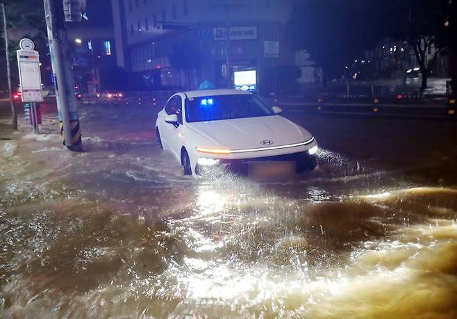 [부산=뉴시스] 호우경보가 발효된 13일 오후 부산 사상구의 한 도로가 침수돼 택시가 힘겹게 이동하고 있다. (사진=부산소방재난본부 제공) 2025.07.14. photo@newsis.com   *재판매 및 DB 금지