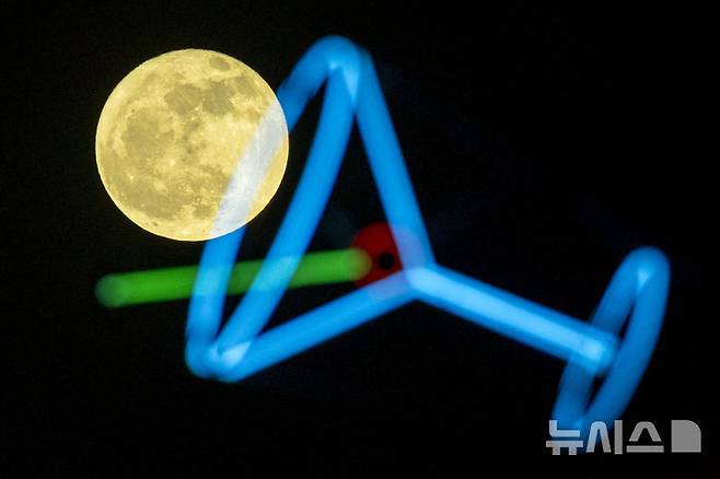 [루이스턴=AP/뉴시스] 10일(현지 시간) 미 아이다호주 루이스턴에서 7월 보름달 '벅 문'(Buck Moon)이 한 상점 간판 뒤로 떠오르고 있다. '벅 문'은 북미 원주민들의 명칭으로 수사슴(buck)의 뿔이 여름철 급속히 자라는 시기를 의미한다. 2025.07.12.