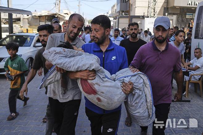 [누세이라트=AP/뉴시스] 13일(현지 시간) 가자지구 중부 누세이라트 알 아우다 병원 인근에서 팔레스타인인이 이스라엘군의 공습으로 사망한 어린이를 운구하고 있다. 2025.07.14.