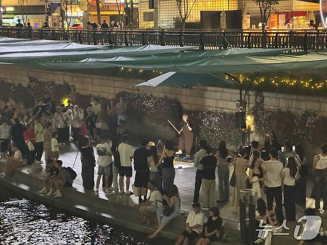 11일 오후 청계천 모전교 일대에서 이뤄진 길거리 바이올린 공연을 외국인 관광객을 비롯한 수십 명의 시민들이 멈춰 서서 관람하고 있다. 2025.07.14/뉴스1 ⓒ 뉴스1 권준언 기자