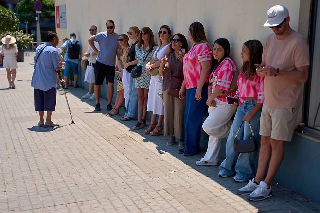 2025년 6월 더운 날씨 속에 스페인 바르셀로나 사그라다 파밀리아 성당을 찾은 관광객들이 벽에 기대어 그늘을 찾고 있다. /연합뉴스