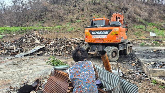 서복래 할머니가 4월 23일 안동시 길안면 대곡1리 보초마을 집터에 들어서는 굴착기를 보면서 장독대 더미를 철판으로 감싸고 있다. 안동=김나연 기자