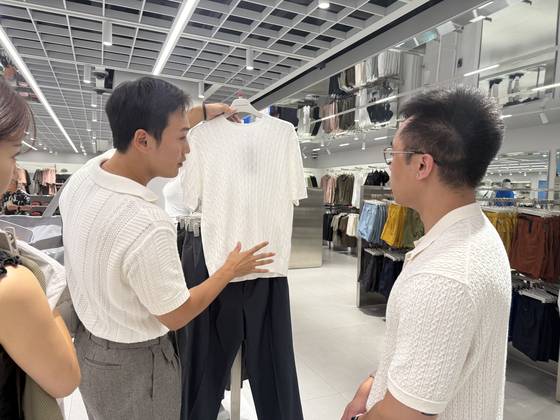 Fashion stylist Rams explains why he chose certain outfits to Jeremy Aban during a shopping tour at Musinsa Standard in Myeong-dong, central Seoul.[WOO JI-WON]