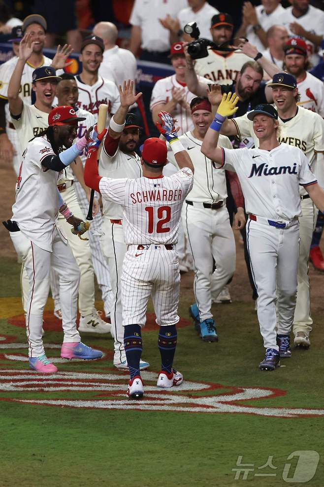 필라델피아 필리스의 카일 슈와버가 16일(한국시간) 열린 2025 메이저리그 올스타전 스윙 오프에서 홈런 3개를 몰아친 뒤 내셔널리그 올스타 동료들의 축하를 받고 있다. ⓒ AFP=뉴스1