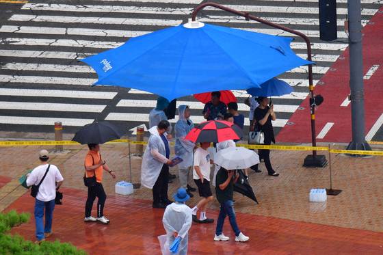 People seek shelter from the rain underneath a parasol on a street in Pohang, North Gyeongsang, on July 16. [NEWS1]