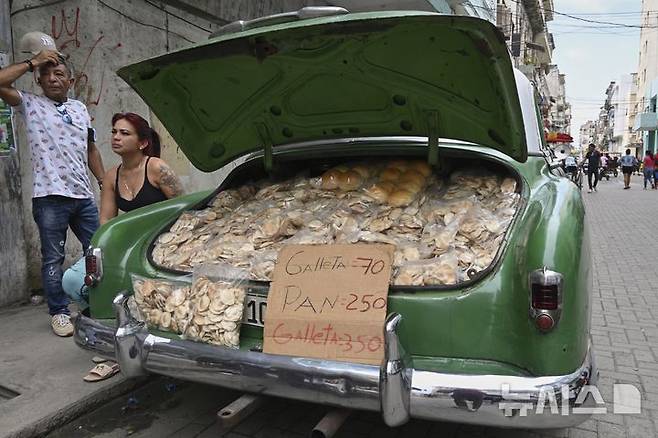 [아바나=AP/뉴시스] 15일(현지 시간) 쿠바 아바나에서 상인들이 미국산 클래식카 트렁크에 수제 감자칩과 빵을 가득 싣고 손님을 기다리고 있다. 2025.07.16.