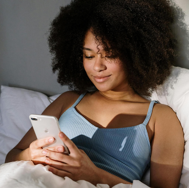 침대에서 스마트폰을 하는 여성