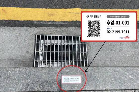 A QR code is posted next to a street gutter in Yongsan District, central Seoul, allowing citizens to easily report an overflowing gutter. [YONGSAN DISTRICT OFFICE]