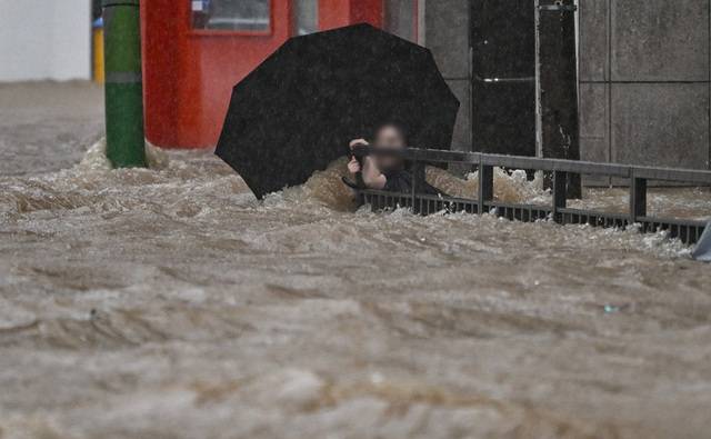한 시민이 17일 오후 광주 북구청 앞을 지나다 갑자기 가슴까지 불어난 물에 휩쓸리지 않기 위해 난간을 잡고 버티고 있다. 기상청은 이날 오후 7시 기준 광주의 일 강수량은 386.4㎜로 평소 7월 한 달 치 강수량이 하루 만에 쏟아졌다고 밝혔다. 뉴시스