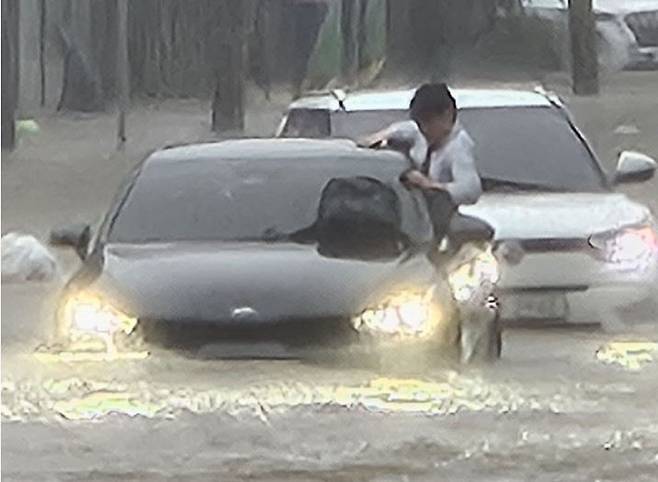 광주지역에 시간당 86㎜ 폭우가 쏟아진 17일 오후 광주 북구청 앞 교차로에서 한 운전자가 차량에서 탈출을 시도하고 있다. 광주=뉴시스