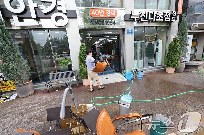 18일 광주 북구 용봉동 전남대 후문 일대가 전날 내린 폭우로 침수돼 한 안경상가의 상인이 물에 젖은 의자를 닦은 후 옮기고 있다. 2025.7.18/뉴스1 ⓒ News1 박지현 기자