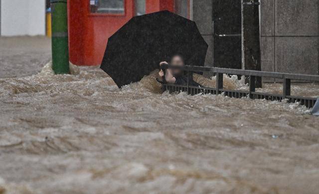 광주 지역에 하루 최고 426.4㎜의 기상 관측 이래 가장 많은 비가 쏟아진 17일 오후, 침수된 광주 북구청 앞 도로에서 한 시민이 물살에 휩쓸리지 않기 위해 철제 난간을 붙잡고 있다. 광주=뉴시스