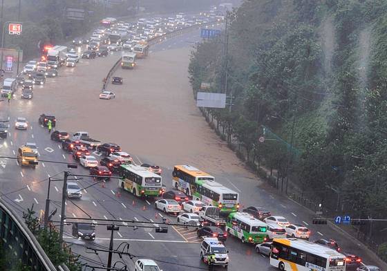 Traffic slows as a road in Hak-dong, Dong District, Gwangju, is submerged in muddy water on July 17 in this photo provided by a reader to Yonhap. [YONHAP]