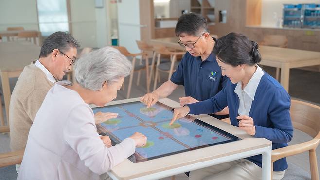 시니어 사용자들이 스마트 돌봄 테이블을 사용하고 있다.