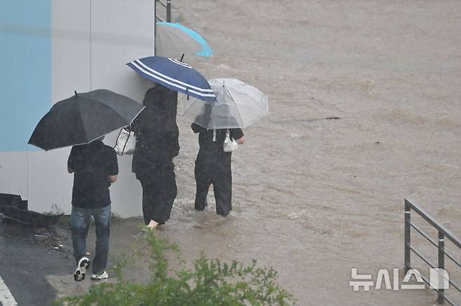 [광주=뉴시스] 이영주 기자 = 광주지역에 하루 최고 311㎜ 폭우가 쏟아진 17일 오후 침수된 광주 북구청 앞 인도 주변으로 시민들이 귀갓길을 재촉하고 있다. 2025.07.17. leeyj2578@newsis.com