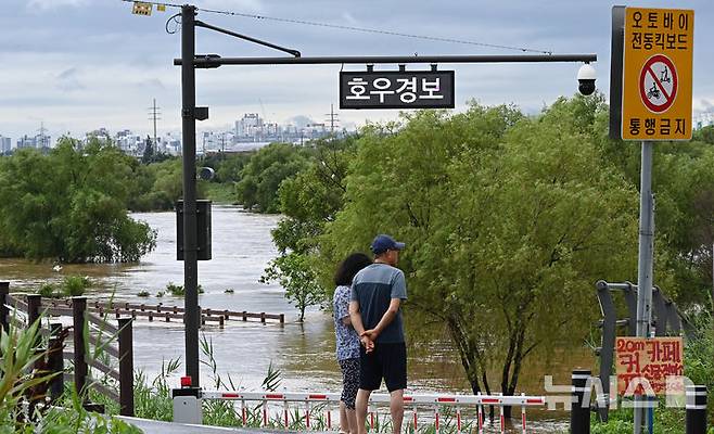 [평택=뉴시스] 김종택 기자 = 경기 남부와 충청지역에 호우경보가 발효된 17일 경기 평택시 안성천 군문교에서 시민들이 집중호우로 불어난 하천을 바라보고 있다. 2025.07.17. jtk@newsis.com