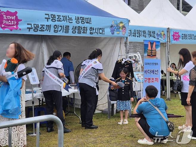 개막 이틀째를 맞은 강원 동해 묵호 도째비 페스타 현장에 마련된 동해해경 구명조끼 입기 캠페인 홍보 부스에서 어린이가 해경 제복을 입으며 즐거운 시간을 보내고 있다. 2025.7.19/뉴스1