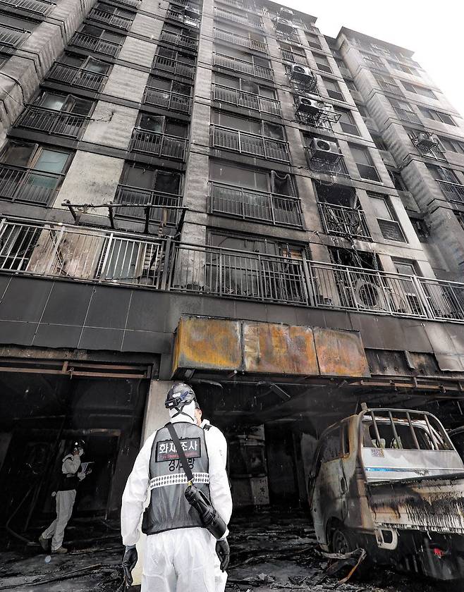 지난 17일 밤 큰불이 나 3명이 숨지고 62명이 다친 경기 광명의 아파트. 소방 당국 관계자들이 불이 처음 시작된 1층 필로티 주차장을 조사하고 있다. 불길이 치솟아 10층 외벽까지 시커멓게 탔다. /장련성 기자