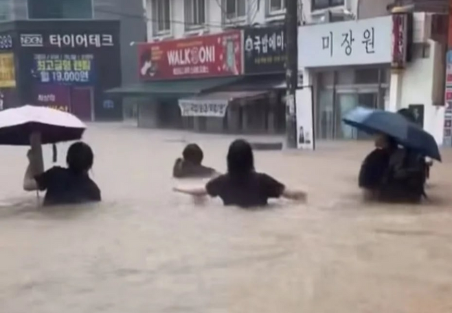 17일 광주광역시에 국지성 집중호우 피해가 잇따른 가운데, 시민들이 허리까지 찬 빗물을 헤치고 길을 건너고 있다.[X(구 트위터) 갈무리]