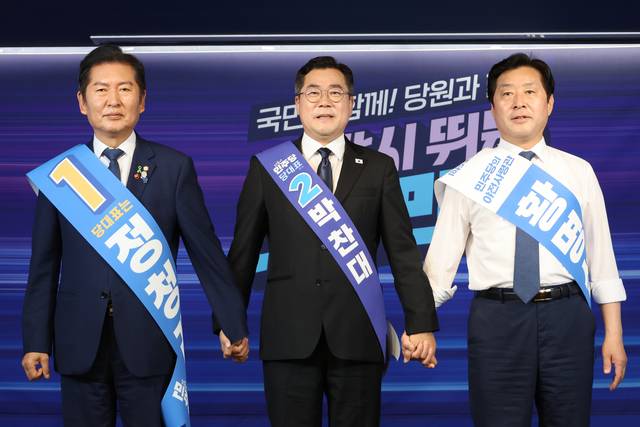 더불어민주당 당대표 선거에 출마한 정청래(왼쪽부터) 의원과 박찬대 의원, 최고위원 선거에 출마한 황명선 의원이 20일 서울 여의도 당사에서 열린 8·2 전당대회 순회 경선 영남권 합동연설회에서 손을 잡고 인사하고 있다. [연합뉴스]