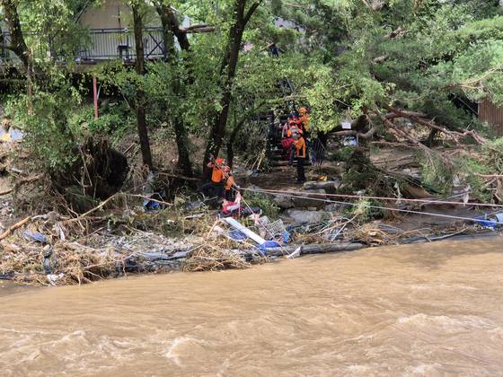 20일 경기도 가평군 조종면 마일리 한 글램핑장에서 집중호우로 불어난 강물에 고립된 관광객을 119 구조대원들이 로프를 이용해 구조하고 있다. 이 캠핑장에선 40대 부부와 중학생 자녀 등 일가족 3명이 투숙했다가 산사태로 매몰됐다는 신고가 접수됐다. 경기도소방재난본부